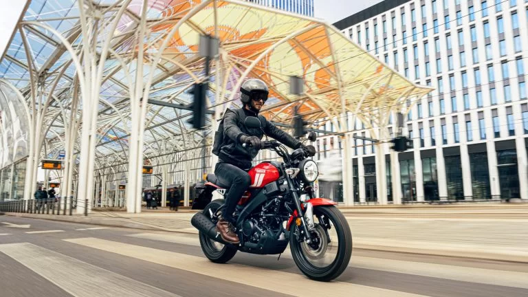 Actiefoto 2023 Yamaha XSR 125 Red Line vooraanzicht met motorrijder die onder overkapping rijdt midden in de stad