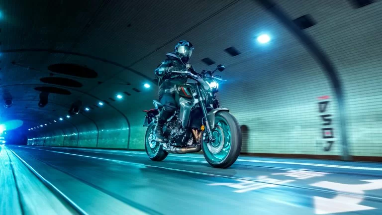 zwarte Yamaha MT-09 met turquoise velgen rijd in het donker door een verlichte tunnel te zien vanuit het voorzijaanzicht