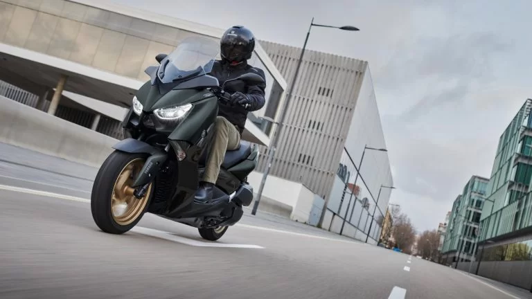 Actiefoto 2022-Yamaha-XMAX300ASP-EU-Dark_Petrol-Action vooraanzicht met motorrijder die in stedelijk gebied rijdt