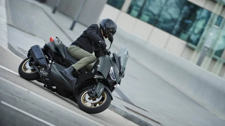 Actiefoto 2022-Yamaha-XMAX300ASP-EU-Dark_Petrol-Action met motorrijder die in stedelijk gebied plat een bocht neemt