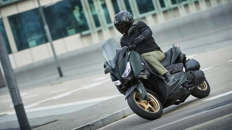 Actiefoto 2022-Yamaha-XMAX300ASP-EU-Dark_Petrol-Action met motorrijder die in stedelijk gebied een bocht neemt