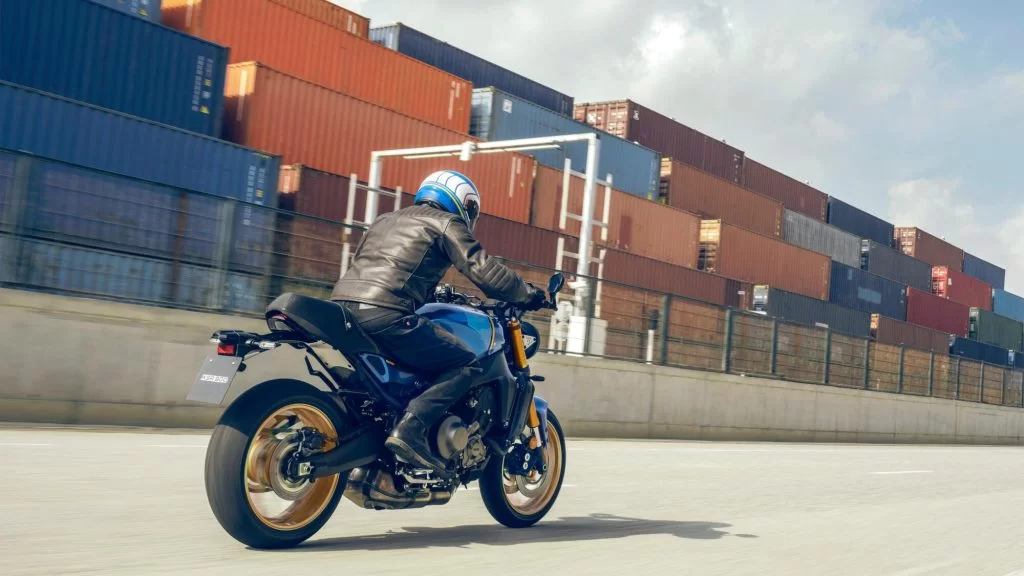 Actiefoto 2022-Yamaha-XS850-EU-Legend_Blue-Action-002-03 met motorrijder die in de haven langs opslag van containers rijdt.