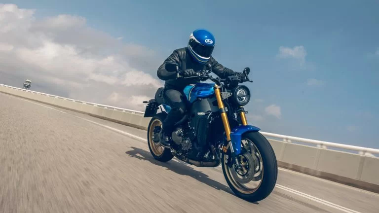 Actiefoto 2022-Yamaha-XS850-EU-Legend_Blue-Action-002-03 met motorrijder die over een weg langs een betonnen vangrail rijdt