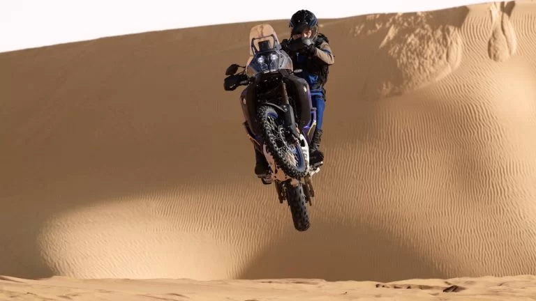 Actiefoto 2023 Tenere 700 World Raid met motorrijder die los van de grond komt met de motor in de woestijn met duinen op de achtergrond