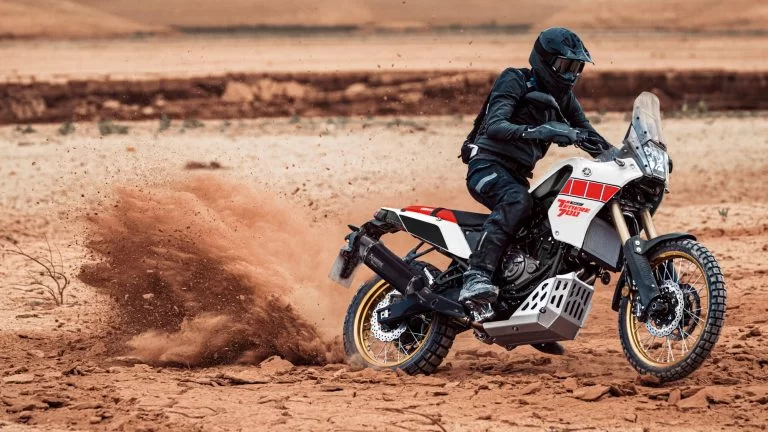 Actiefoto 2023 Yamaha Ténéré 700 zijaanzicht van motorrijder die gravel doet opstuiven door gas te geven in een off-road gebied