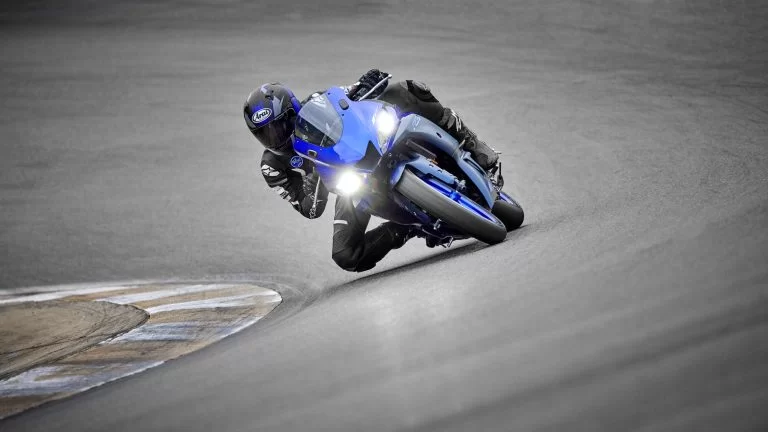 blauwe Yamaha YZF-R3 rijd door een bocht op een circuit te zien vanaf het vooraanzicht