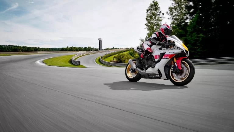 Wit met rode Yamaha YZF-R1 rijd over een circuit uit een bocht te zien vanuit het zijaanzicht