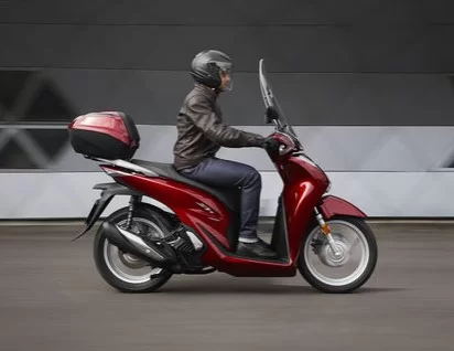 actiefoto van motorrijder op een rode 2023-Honda-Sh150i-motorscooter