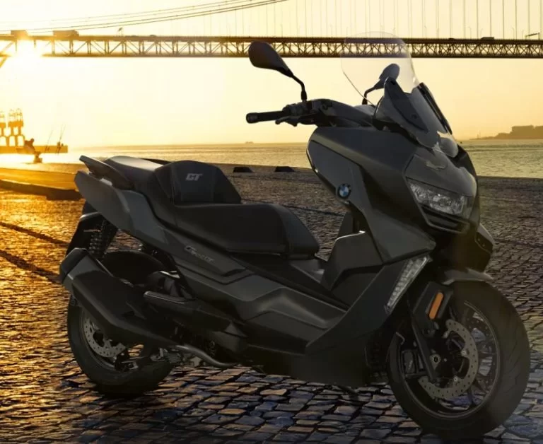 lifestylefoto van een 2023-bmw-c400-gt-motorscooter met een grote hangbrug en zonsondergang op de achtergrond