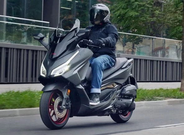 actiefoto van de 2023-honda-forza-125-motorscooter met motorrijder in de stad