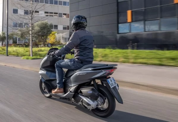 actiefoto van 2023-honda-pcx-125-motorscooter in de stad met motorrijder