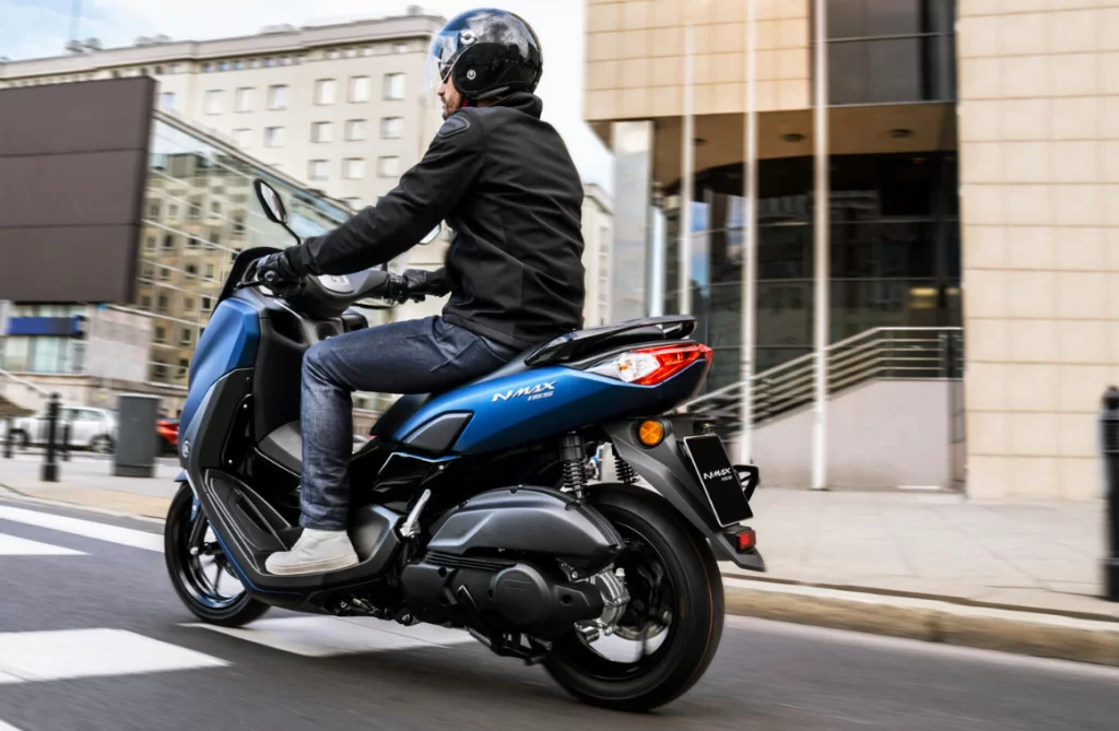 Motorscooterrijder op de 2023 blauwe Yamaha nmax 155 rijdend door de stad