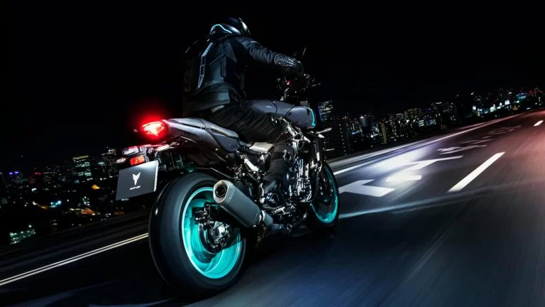 motorrijder rijdt op een mt-10 door het donker over straat met felgekleurde cyan velgen