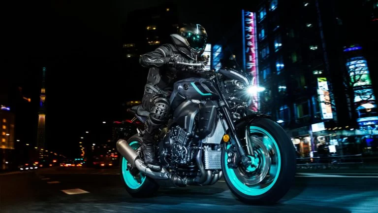 motorrijder rijdt door de stad in de nacht op een yamaha mt-10 met felgekleurde cyan velgen