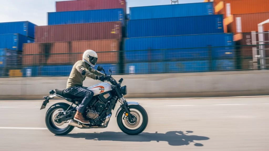 actiefoto motorrijder rijdt op een urban motorfiets langs zee containers