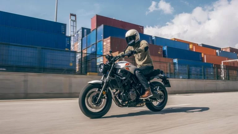 actiefoto motorrijder op een urban motorfiets rijdt langs zeecontainers