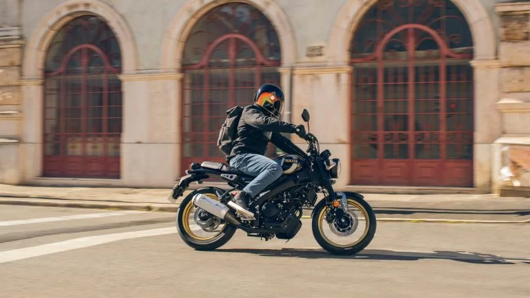 motorrijder rijdt langs een gebouw op een retro motorfiets
