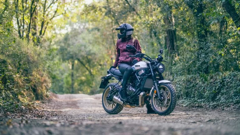 vrouwelijke motorrijdster zit op haar sport Heritage motor op een bospad