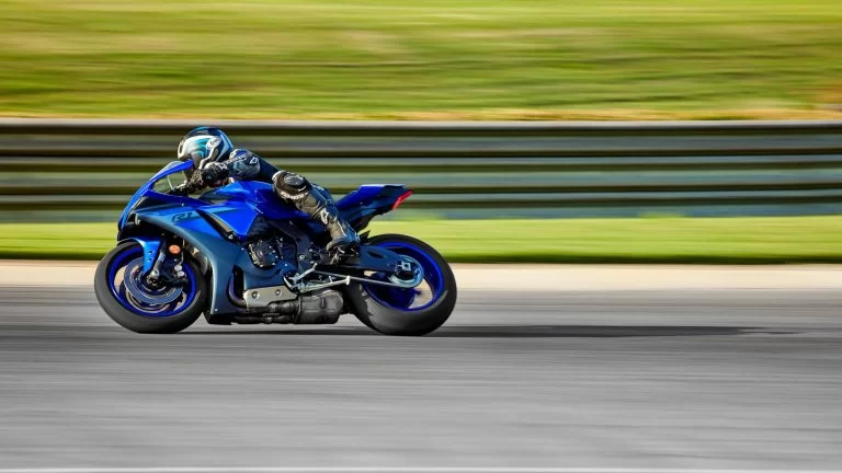 Motorrijder op een blauwe supersport motor rijdt over het circuit te zien vanaf de zijkant
