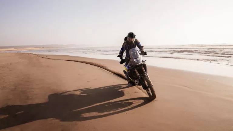 adventure motor met motorrijder die over het strand rijdt langs de zee