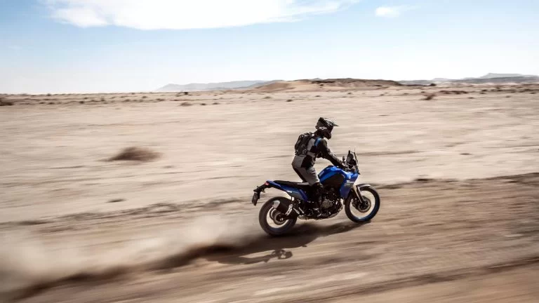 Motorrijder rijdt op een blauwe adventure motor door de woestijn