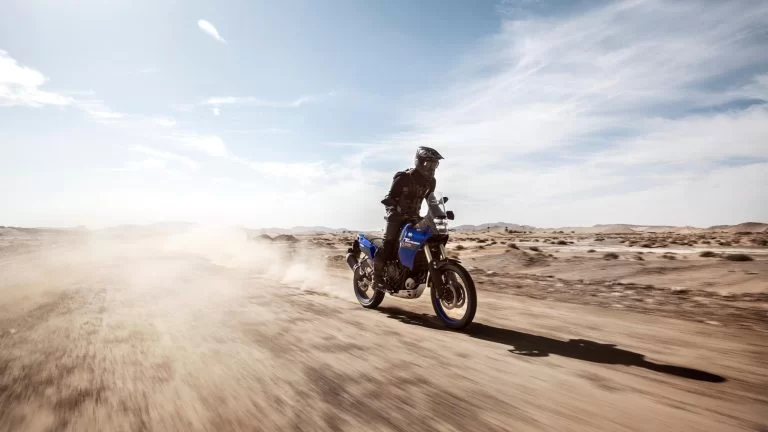 motorrijder rijdt met een blauwe adventure motor door de woestijn