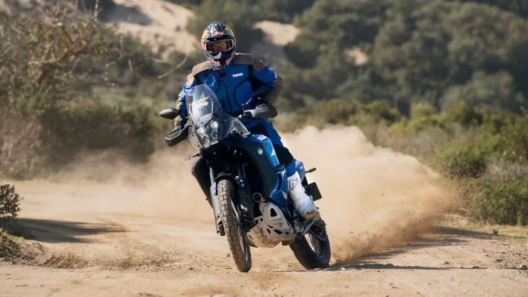 motorrijder rijdt op een blauwe adventure motor over een zandpad