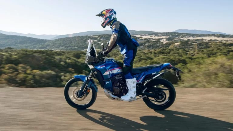 motorrijder rijdt op een blauwe adventure motor over een zandpad