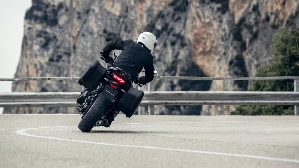 Motorrijder rijdt een bocht in met bergen op de achtergrond