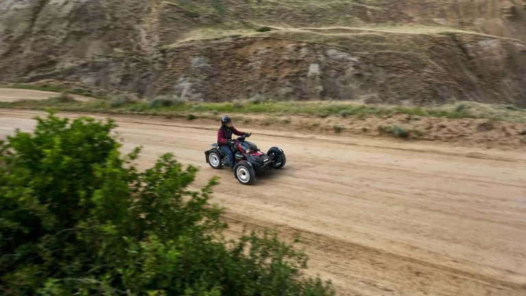 driewieler met bestuurder rijdt over een onverharde zandweg