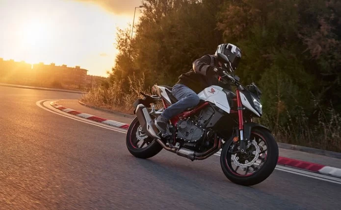 Honda CB Hornet 750 actiefoto van motorrijder die om een bocht heen rijdt met zonsondergang op de achtergrond