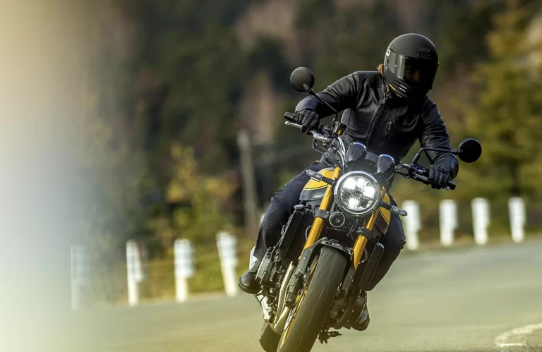 Actiefoto geelzwarte Kawasaki Z900 RS met motorrijder die een bocht neemt