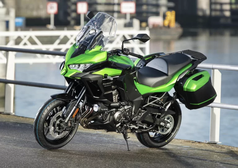 Lifestylefoto 2023 Kawasaki Versys 1000 S met water en hek op achtergrond