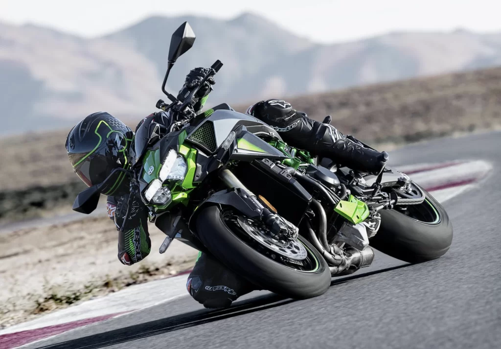 Actiefoto 2023 Kawasaki ZH2 groen schuin vooraanzicht op racecircuit. Motorrijder neemt bocht.