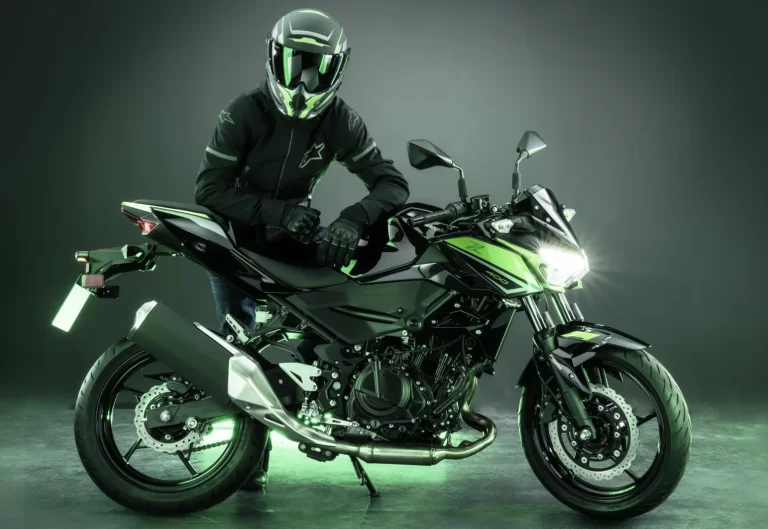 Studiofoto 2023 Kawasaki Z400 met motorrijder leunend op het zadel en groene sfeerverlichting.