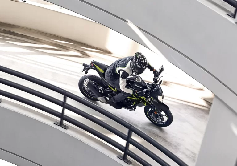 Actiefoto 2023 Kawasaki Z125 zijaanzicht met motorrijder rijdend op cirkelende uitrit in parkeergarage