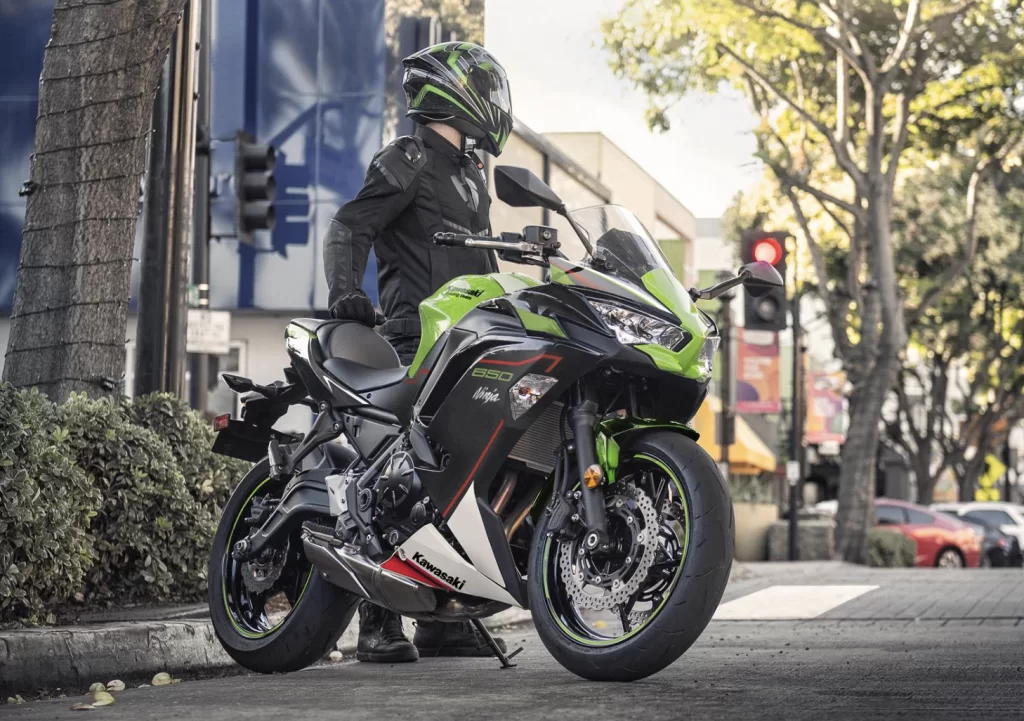Lifestylefoto 2023 Kawasaki Ninja 650 met motorrijder die naast de motor staat en achterom kijkt in stedelijk gebied