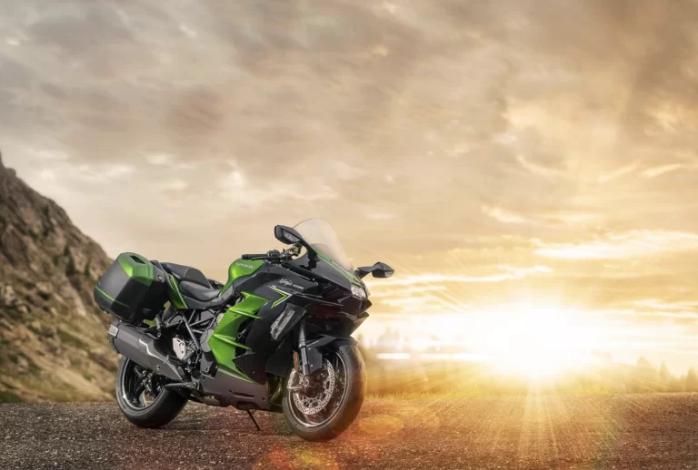 Lifestylefoto Ninja H2 SX met motor links op voorgrond en zonsondergang op achtergrond