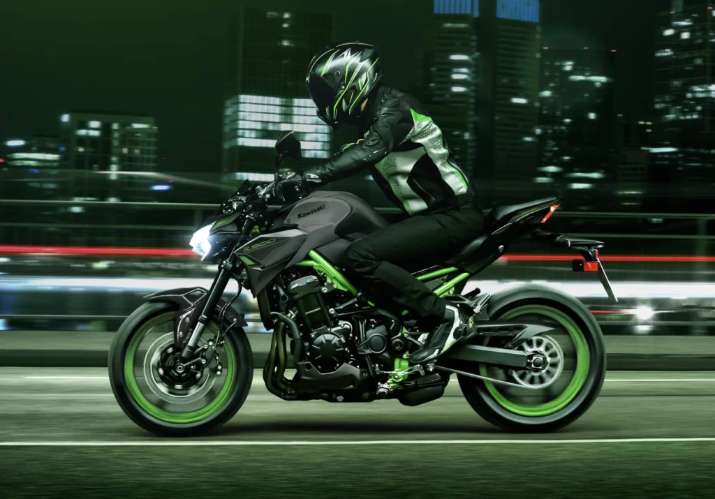 Actiefoto 2023 Kawasaki Z900 zijaanzicht met motorrijder die in de avonduren op ring van de stad rijdt.