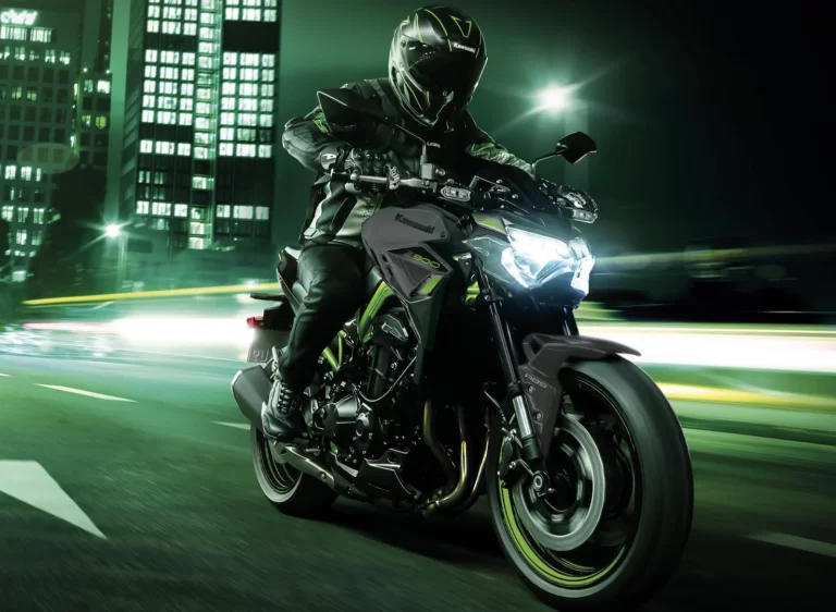 Actiefoto 2023 Kawasaki Z900 70kW met motorrijder die in de avond in stedelijk gebied met hoge snelheid over een weg rijdt