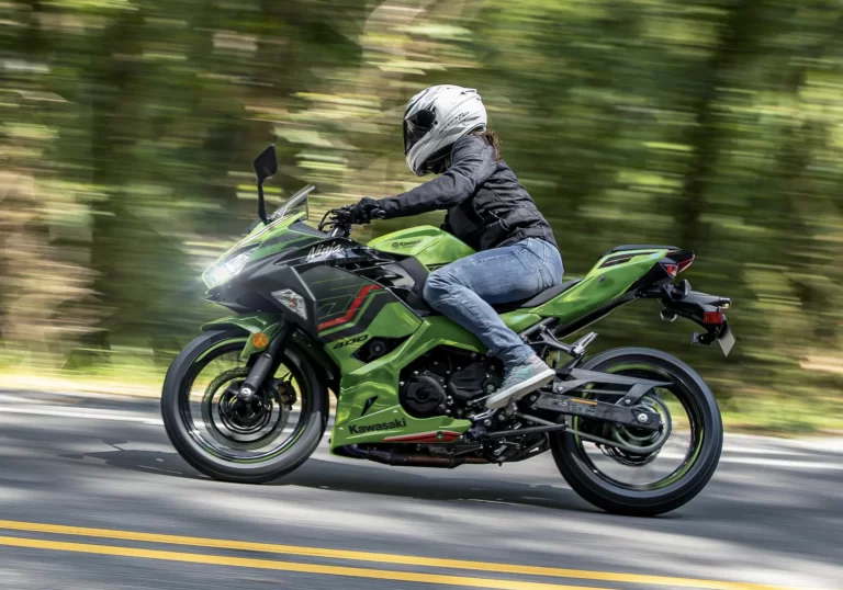 Actiefoto 2023 Kawasaki Ninja 400 zijaanzicht met motorrijder op weg in bosrijke omgeving