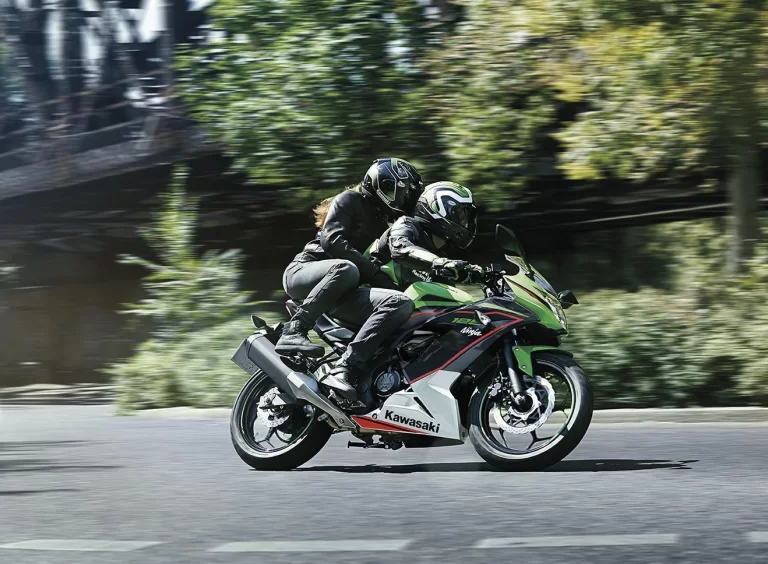 Actiefoto 2023 Kawasaki Ninja 125 met motorrijder en buddy die een bocht nemen.