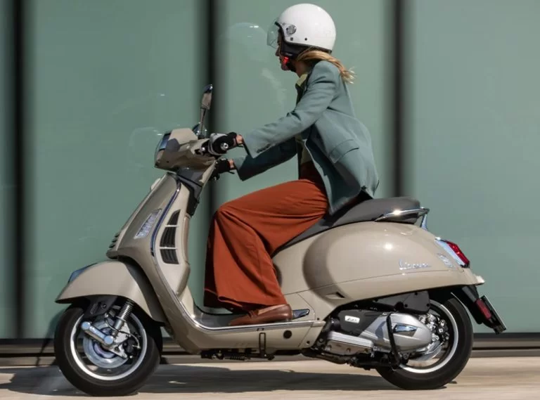 actiefoto van dame op een grijzige vespa gts motorscooter